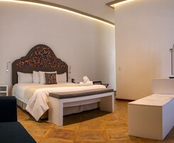 Een moderne hotelkamer met een groot bed, een bankje en een kleine tafel.