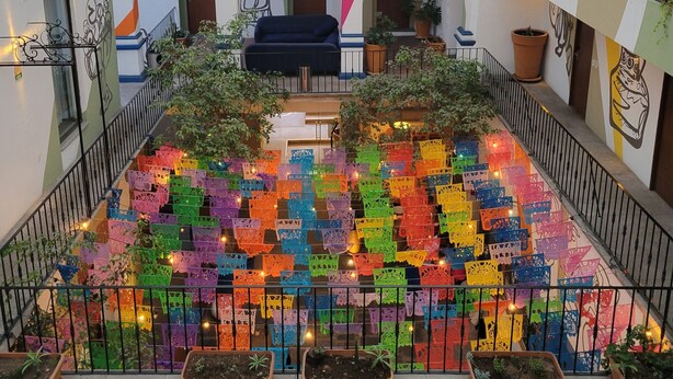 Un atrium ampli amb una exhibició de fanals de paper de colors, una zona d'estar central i plantes en testos.