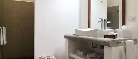 A bathroom with a white sink, a mirror, a shower, and a towel rack.