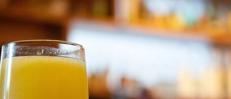 A glass of orange juice with a blurred background of a bar area.