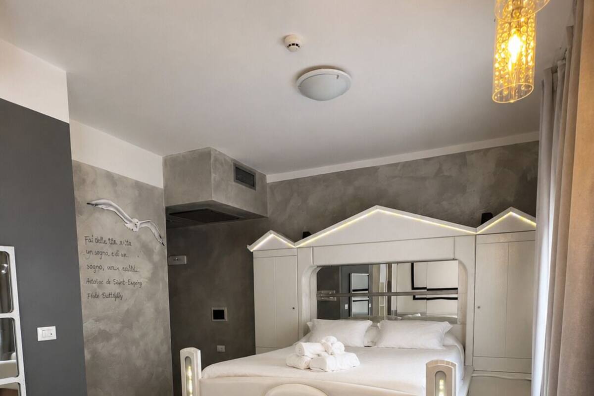 Una camera da letto moderna con vasca idromassaggio integrata, uno specchio grande e un lampadario.