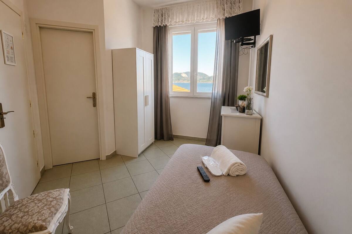 Camera d'hotel con un letto, una sedia, una scrivania con televisore e una finestra vista.
