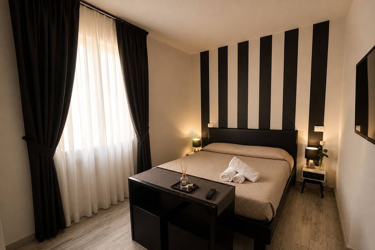 Una camera d'albergo con un letto, comodini, una scrivania e una finestra con tende.