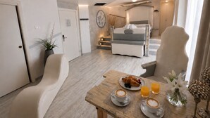 A modern hotel room with a bed, a dining table with breakfast, and a staircase leading to an upper level. - Hotel Butterfly - We Suite (Viareggio)
