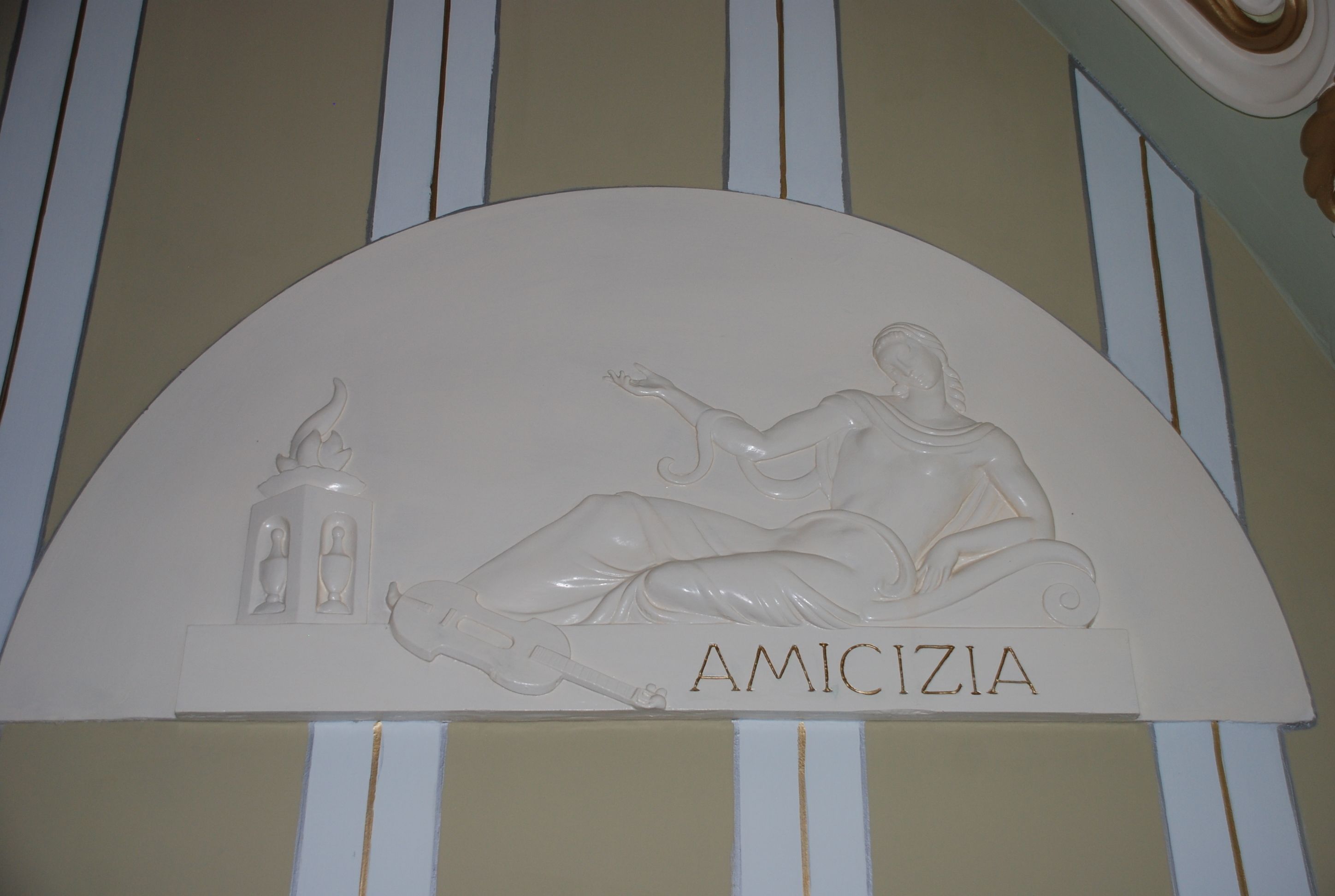 A wall with a relief sculpture of a reclining figure and the word "AMICIZIA".