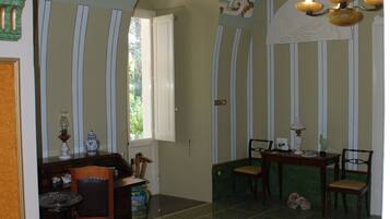 A dining area with a table and chairs, a chandelier, and a window with curtains.
