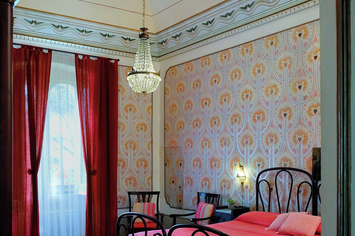 A bedroom with a bed, a nightstand, a mirror, and a chandelier.