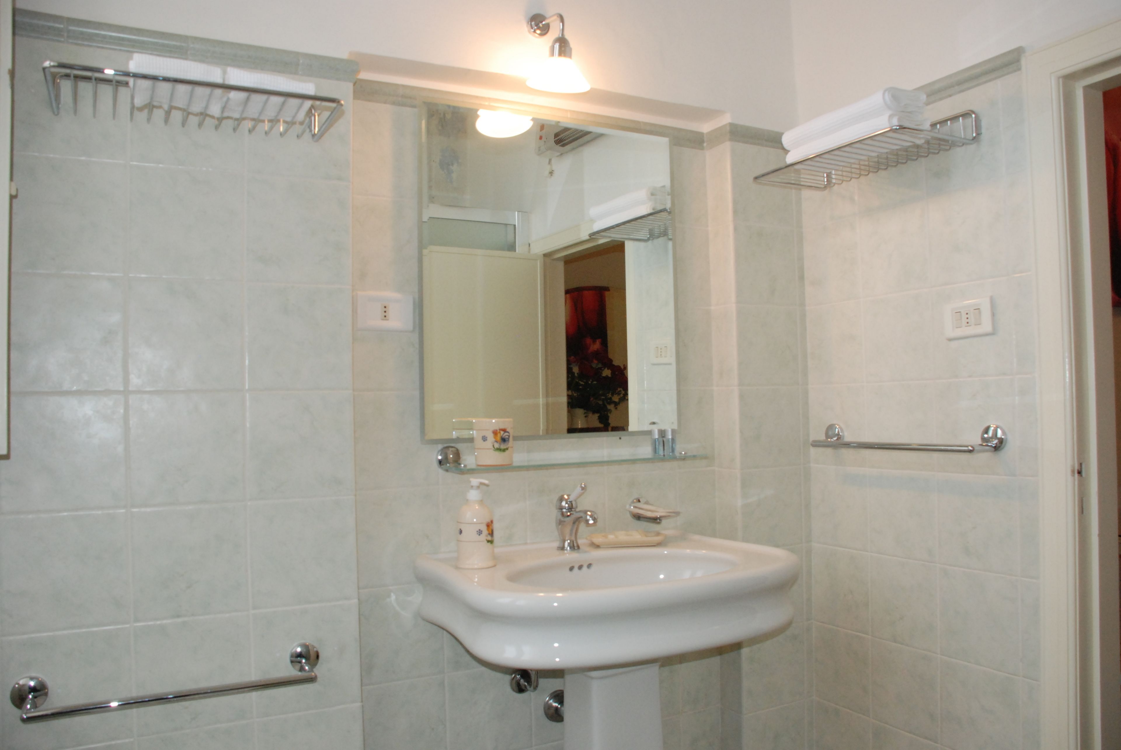 Een badkamer met een wastafel, spiegel en handdoekhouder.