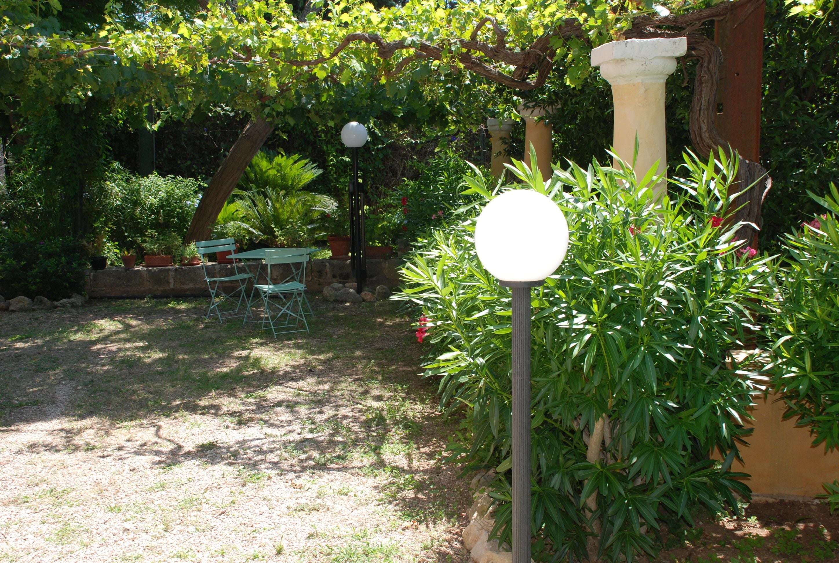 Un jardí amb una pèrgola, una taula i cadires, i un fanal.