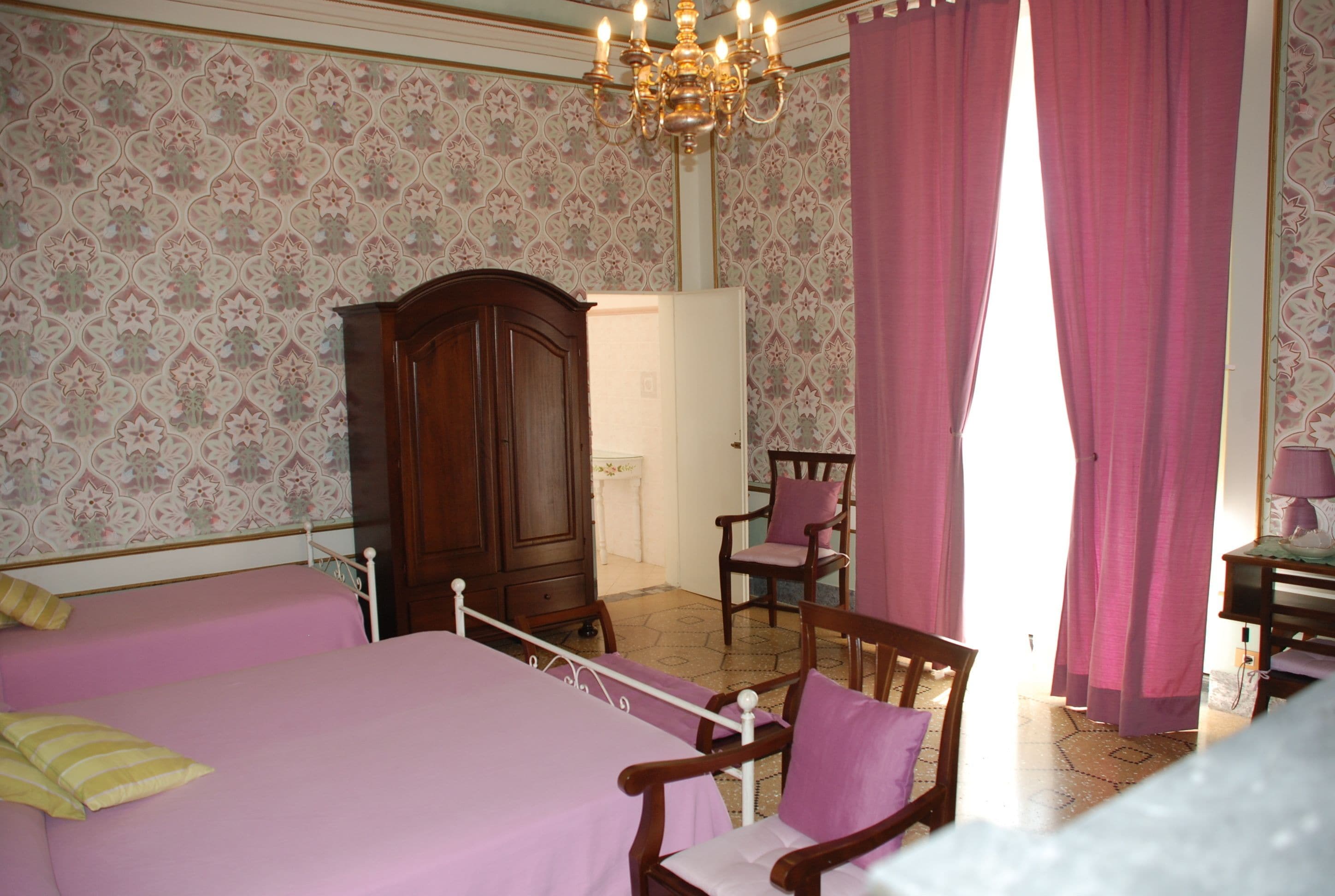 Een slaapkamer met twee bedden, een houten garderobe, een stoel en een kroonluchter.