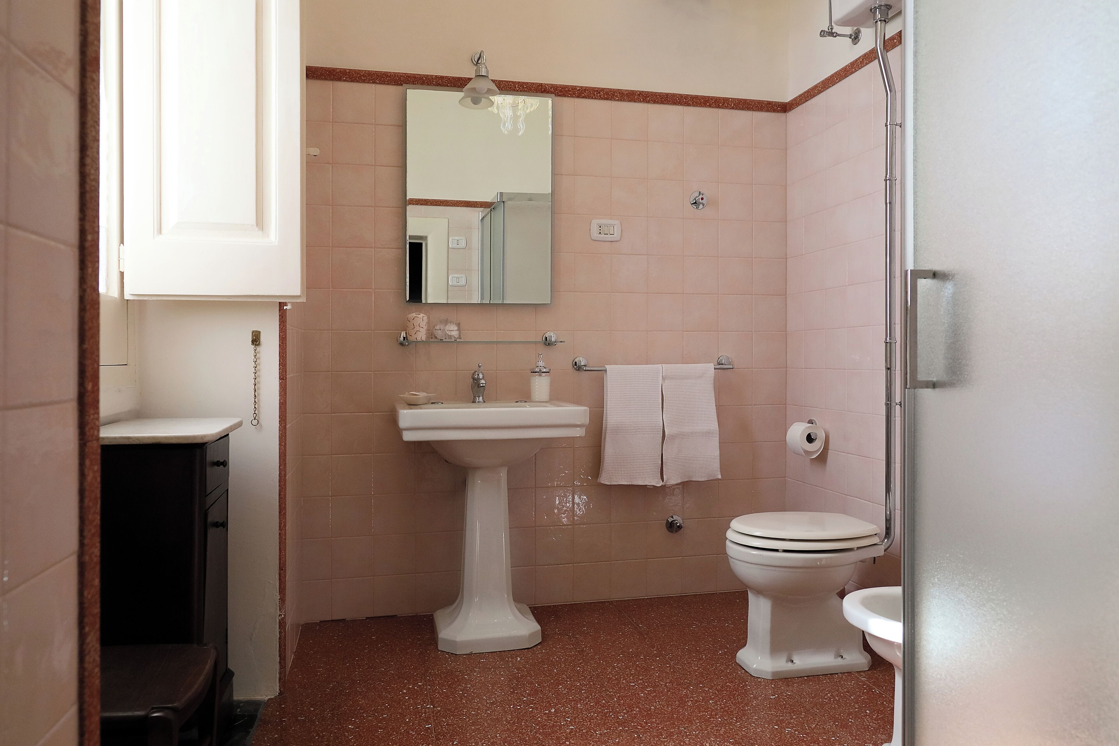 Et badeværelse med et håndvaskestel, toilet og brusebad.