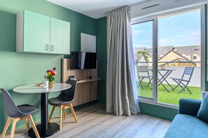 A modern room with a dining table, chairs, a TV, and a view of the outside.