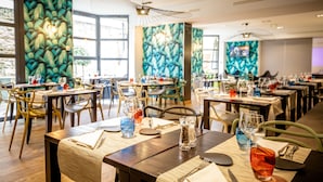 Un restaurante con varias mesas, cada una con cubiertos, vasos y una botella de agua.