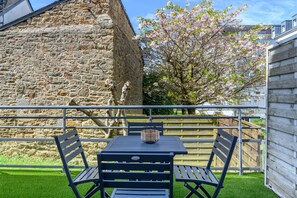 A balcony with a stone wall, a wooden fence, and a tree with pink blossoms.