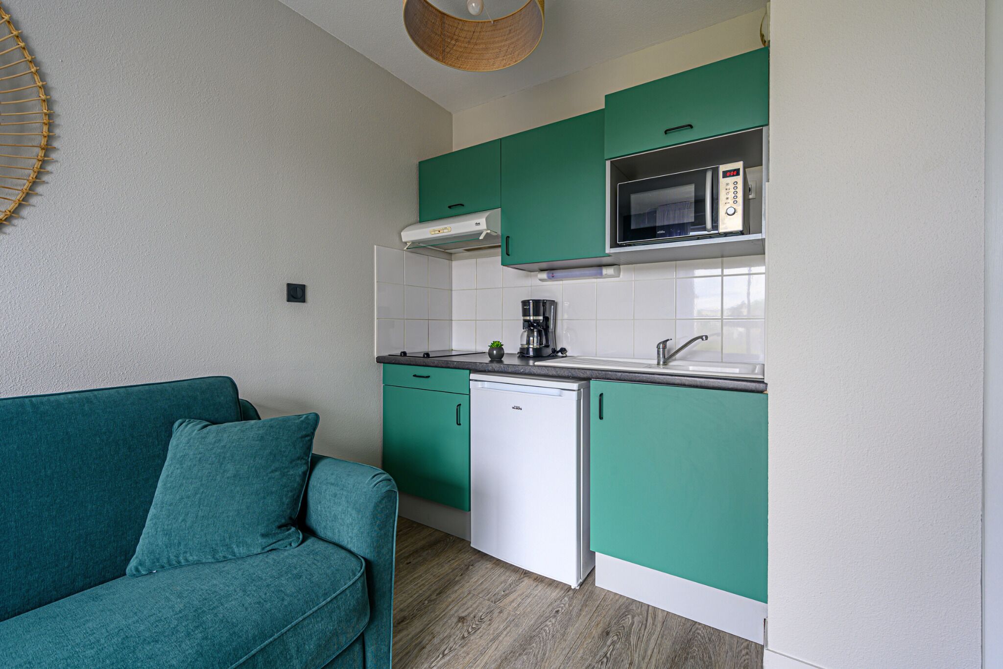 A compact kitchen with teal cabinets, a white dishwasher, and a microwave.