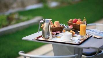 A breakfast tray with coffee, pastries, and juice on an outdoor table.