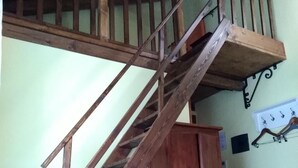 Un dormitorio con escalera de madera, cama, armario y perchero en la pared.
