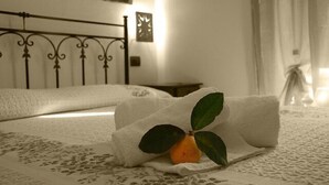 Una cama bien hecha con una toalla doblada y una naranja con hojas.