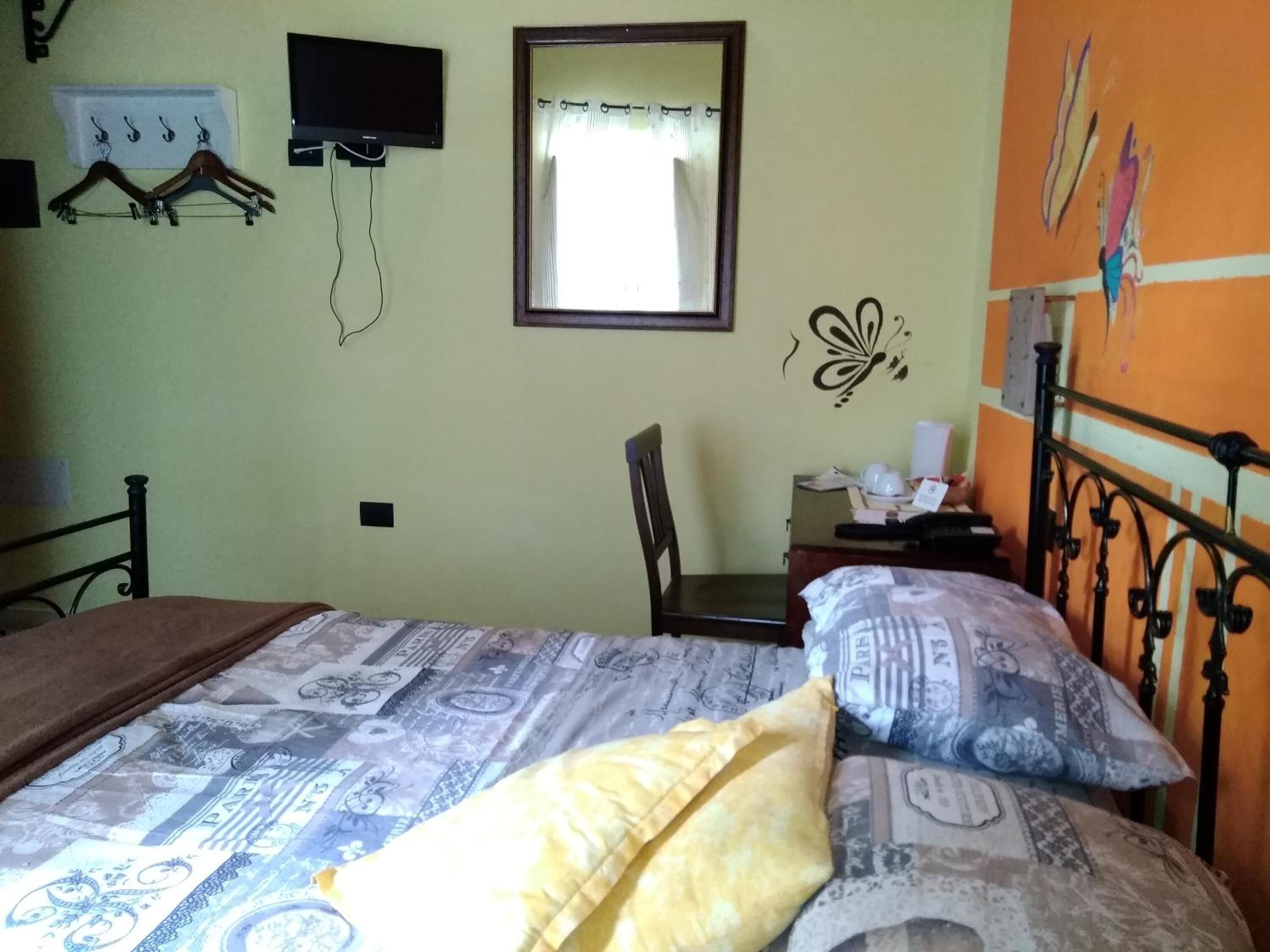 Une chambre à coucher comprenant un lit, une chaise, un bureau et un téléviseur fixé au mur.