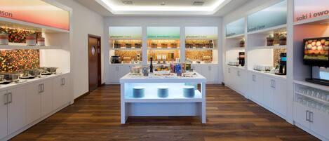 Una cocina moderna con armarios blancos, una isla central con lavamanos y diversos electrodomésticos.