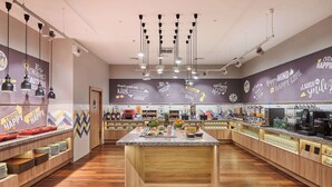 Un café moderne doté d’un îlot central, de comptoirs en bois et de décorations murales inspirantes.