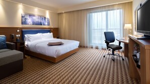 Une chambre d’hôtel avec un grand lit, un bureau avec une télévision, une chaise et un canapé.