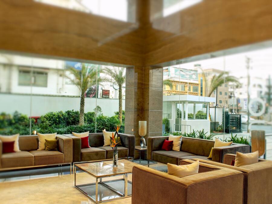 A modern lobby with comfortable seating, a glass coffee table, and a view of the cityscape.