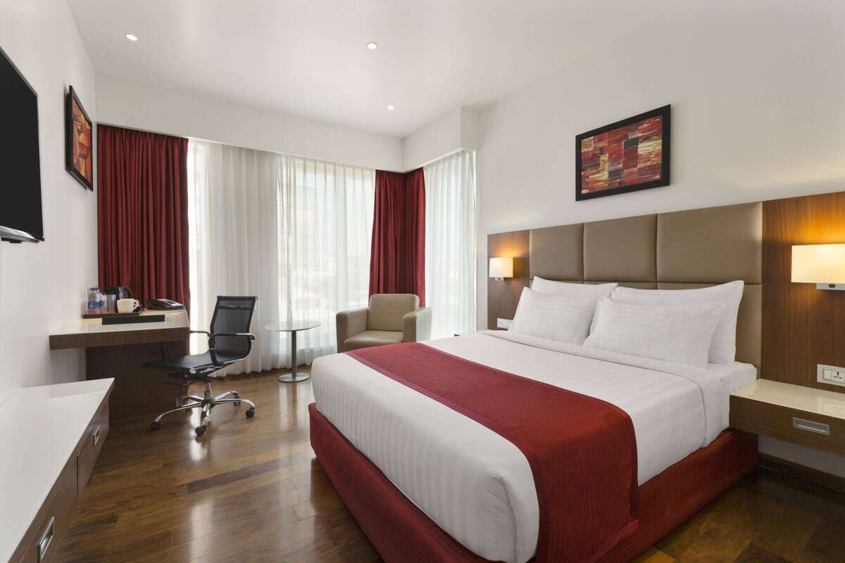 Een hotelkamer met een groot bed, een bureau, een stoel en een televisie.
