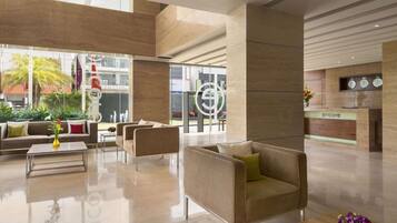 A modern lobby with a reception desk, seating area, and a large window offering a view of the outdoors.