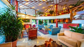 A spacious lobby with a high ceiling, multiple seating areas, and a central coffee table. - Resort Arcobaleno All Inclusive (Porto Seguro)