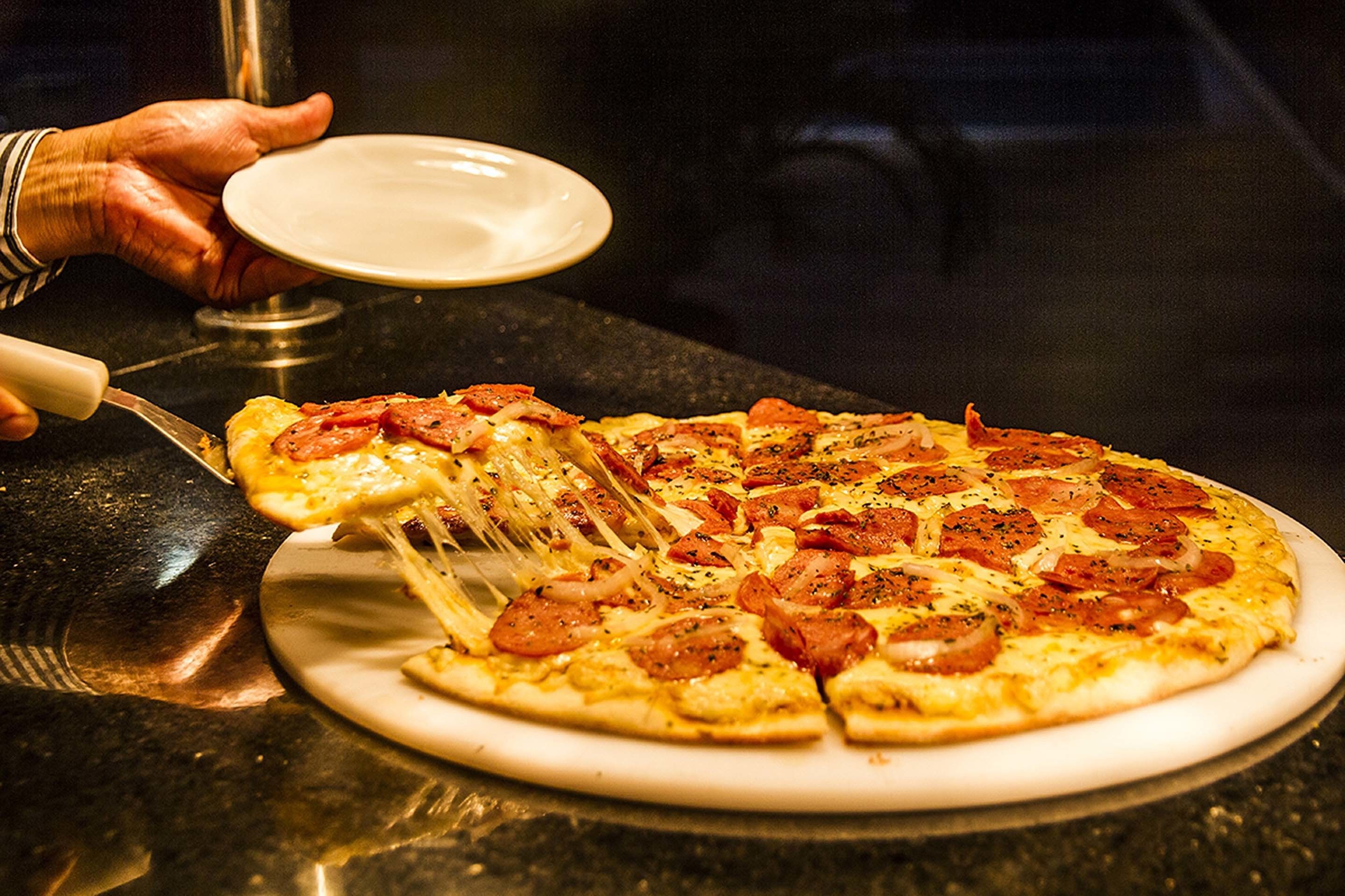 Uma pizza com fatias de pepperoni em um prato branco.