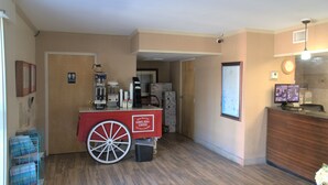 A hotel lobby with a coffee cart, a reception desk, and a framed map on the wall. - Eastern Shore Motel (Daphne)