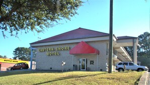 The Eastern Shore Motel with a red awning, a visible entrance, and a parked car in front. - Eastern Shore Motel (Daphne)