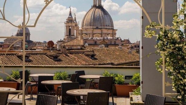 Una terraza con mobiliario exterior y vistas a una gran cúpula y campanario.