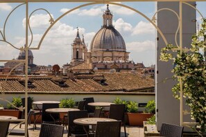 A terrace with outdoor seating and a view of a large dome and bell tower. - Antica Dimora Delle Cinque Lune (Rome)