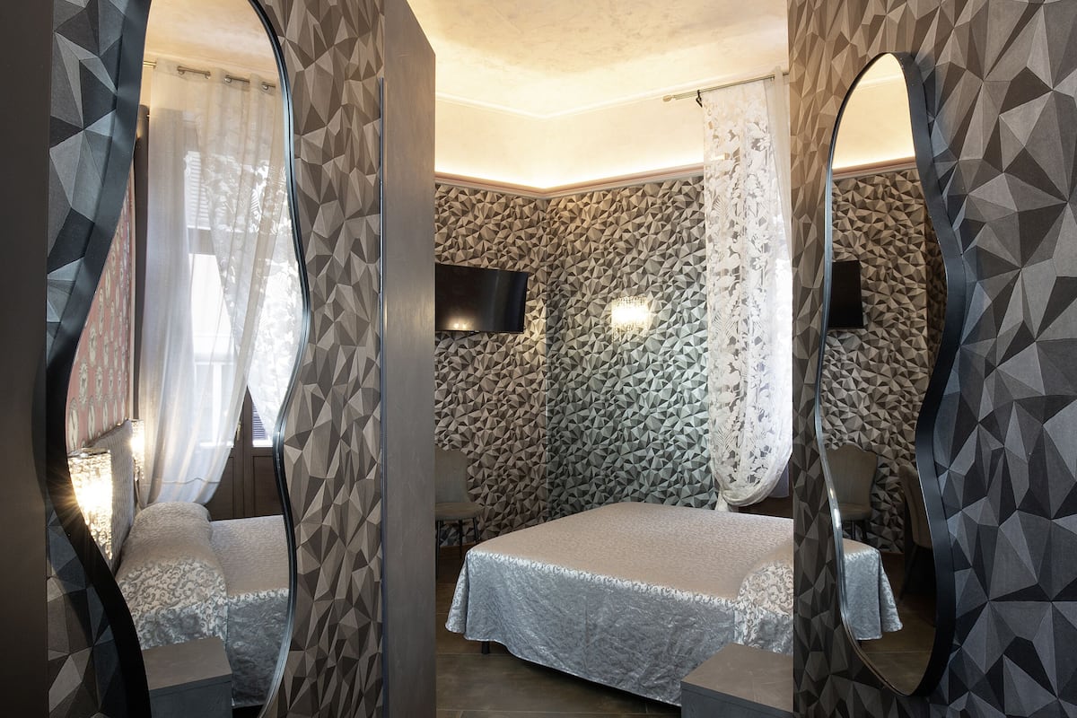 Un dormitorio con cama, televisor y espejo.