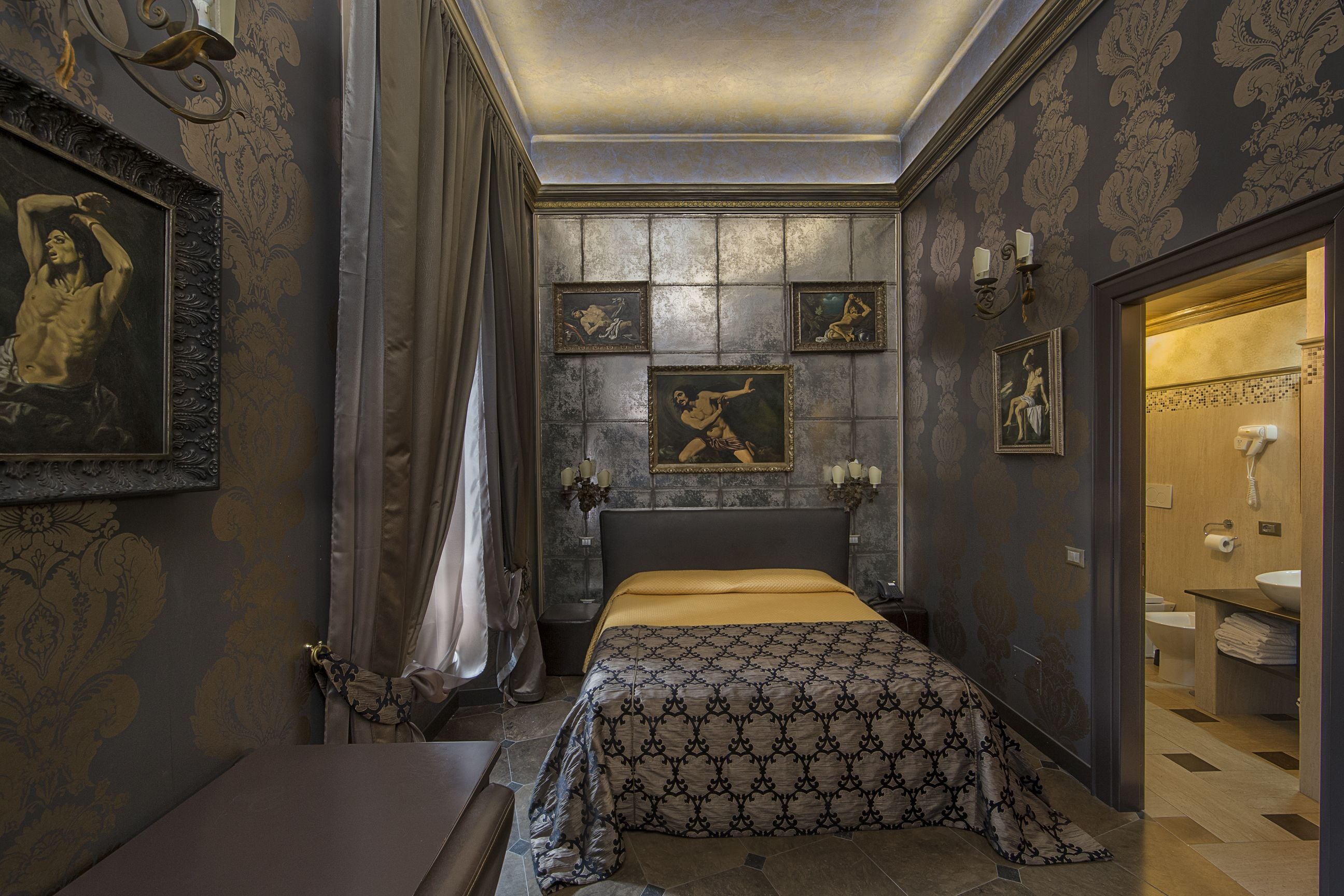 A bedroom with a bed, a nightstand, a dresser, and a bathroom visible through an open door.