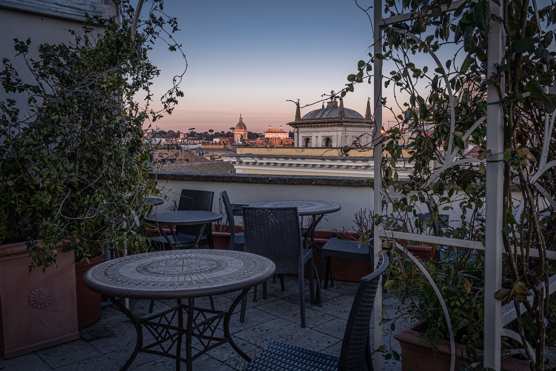 A terrace with a table and chairs, overlooking a historic building with a dome and arches.