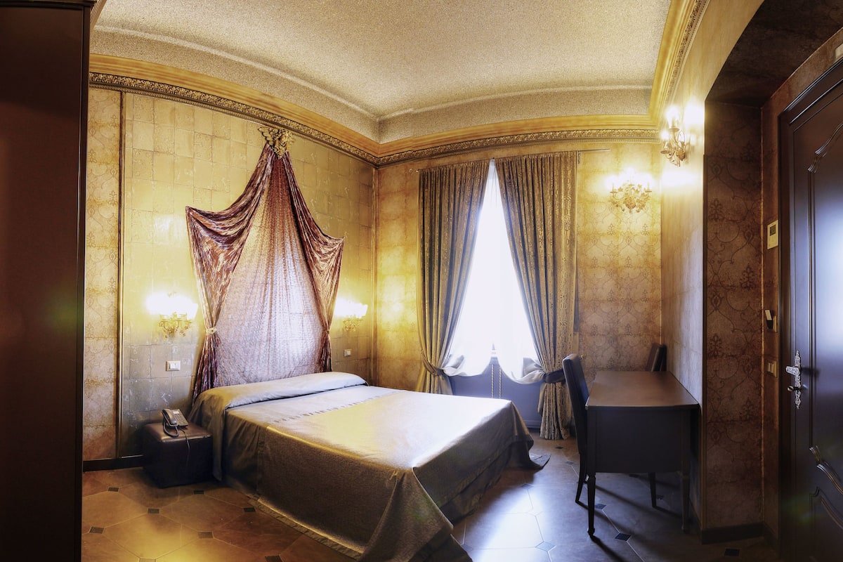 Un dormitorio lujoso con una cama grande, un escritorio y una silla.