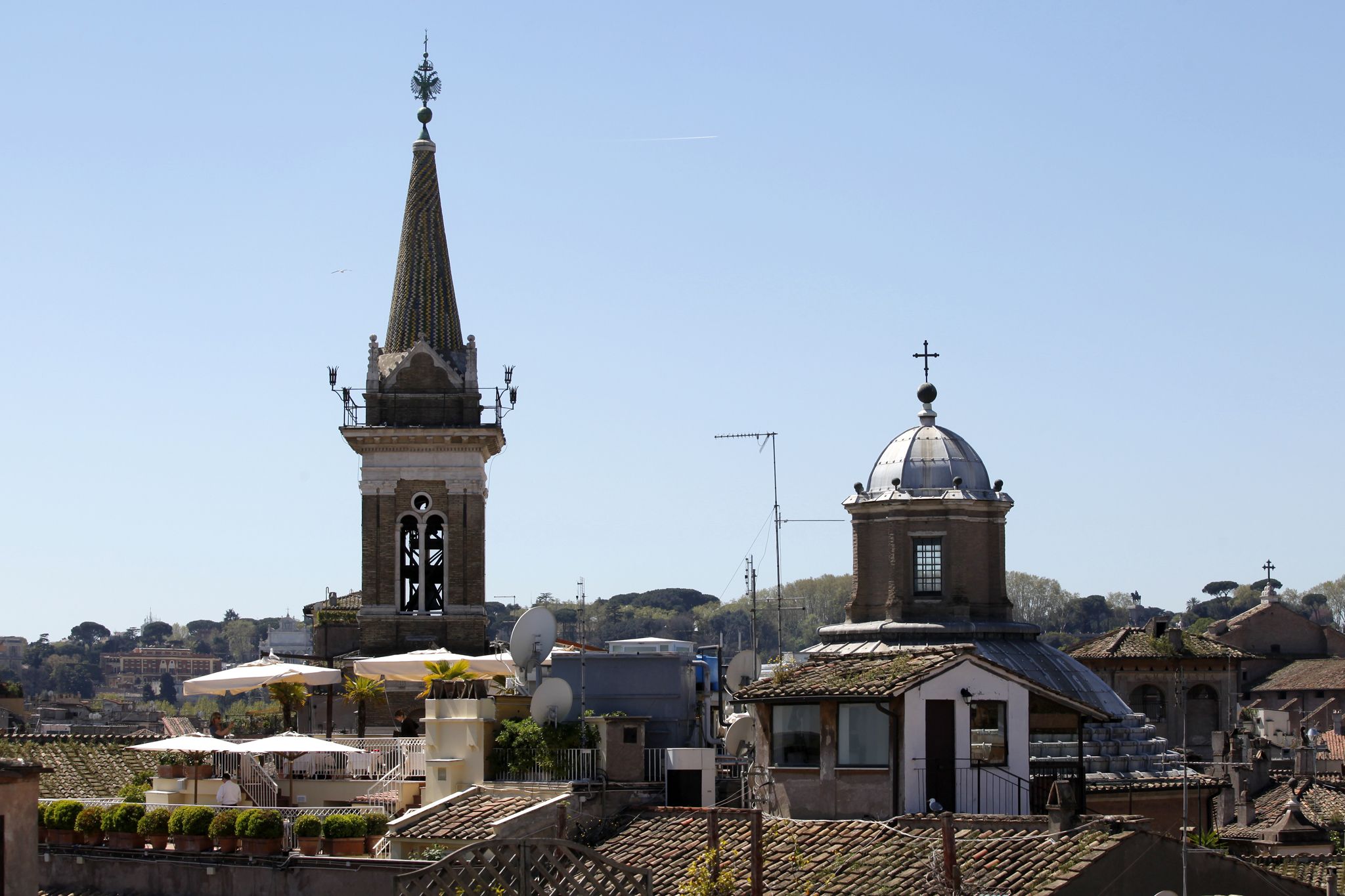 A church with a tall spire and a dome, surrounded by residential buildings and satellite dishes.