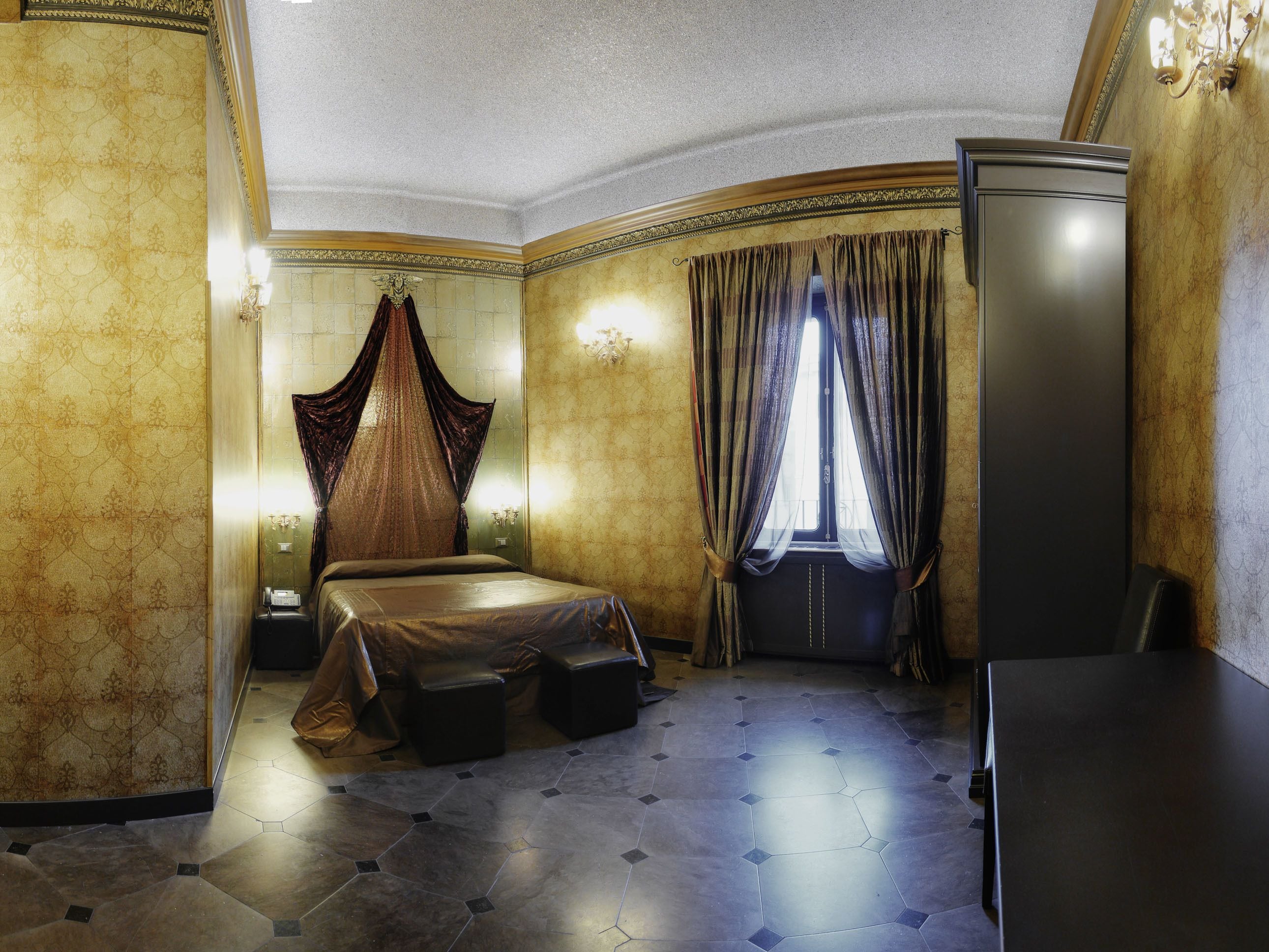 A bedroom with a bed, a nightstand, a wardrobe, and a large window with curtains.