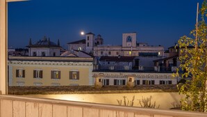 Un paisaje urbano nocturno con edificios históricos, una destacada torre del reloj y una luna visible.