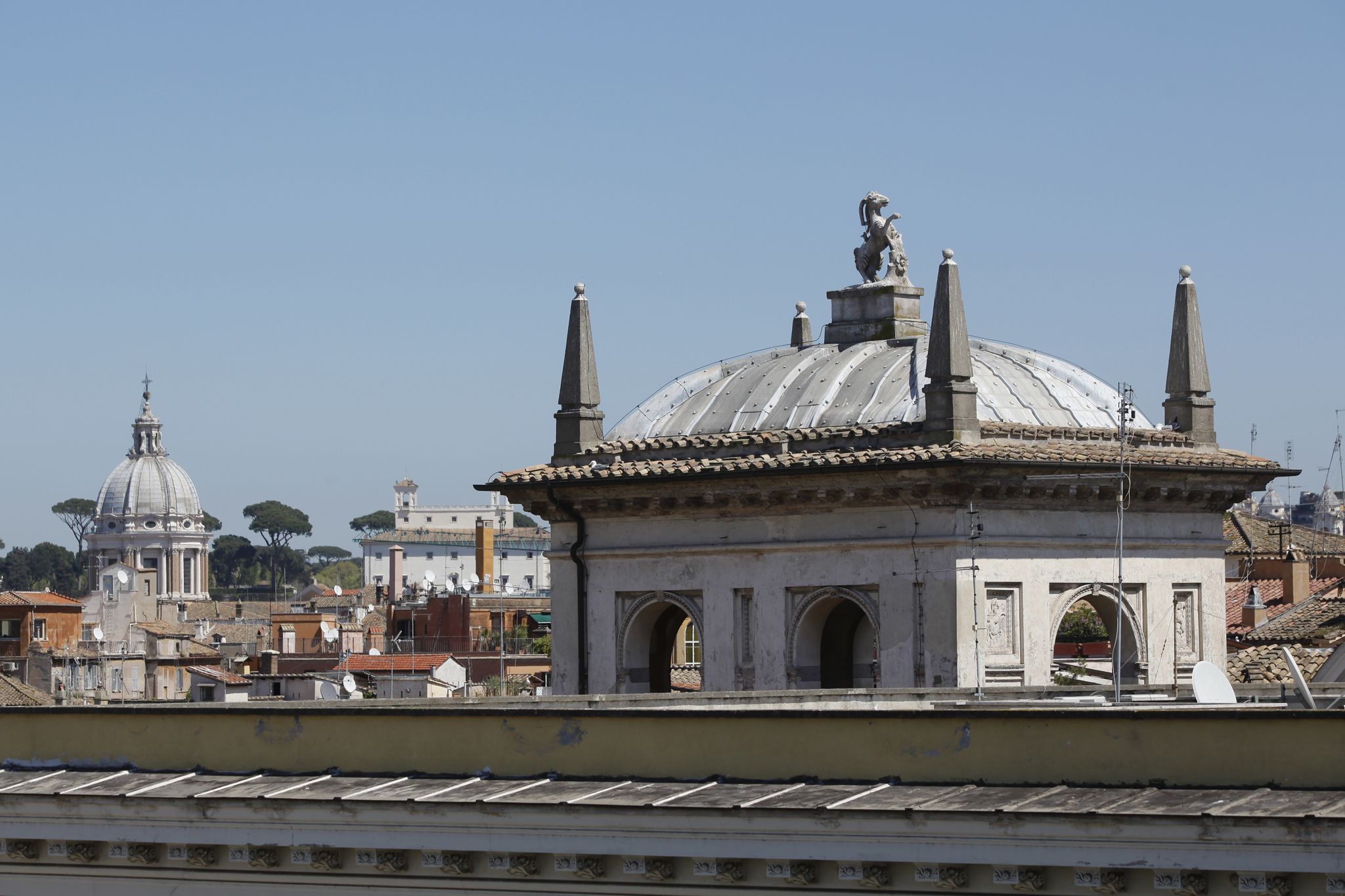 Un edificio histórico con una cúpula y estatuas, rodeado de otros edificios.