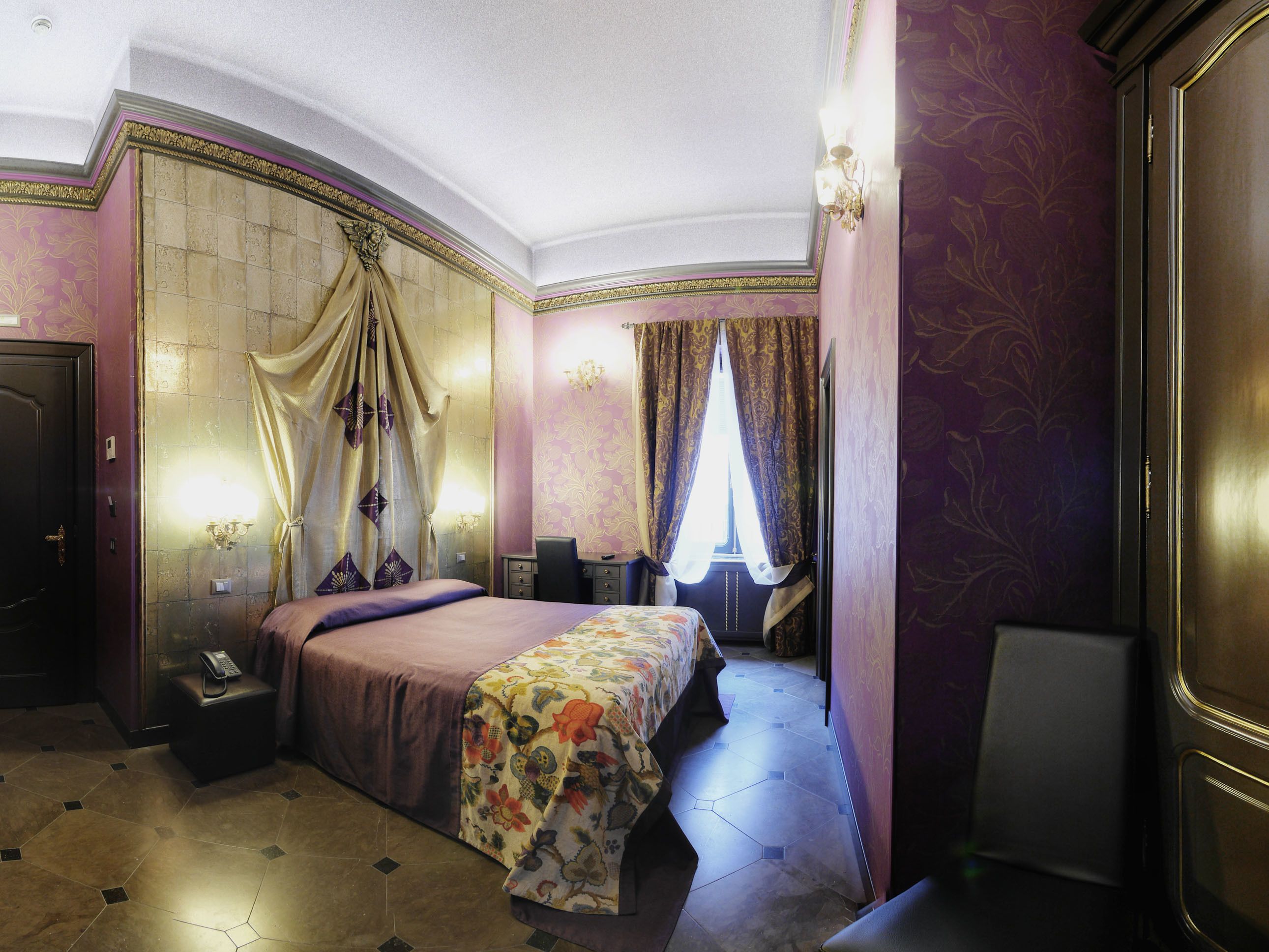 A luxurious bedroom with a large bed, a bedside table, a chair, and a desk.