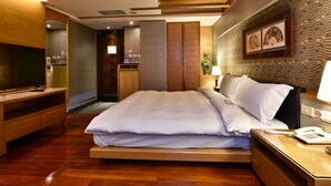 A hotel room with a large bed, wooden furniture, a TV, and a desk with a phone. - Waikoloa Hotel (Taipei)
