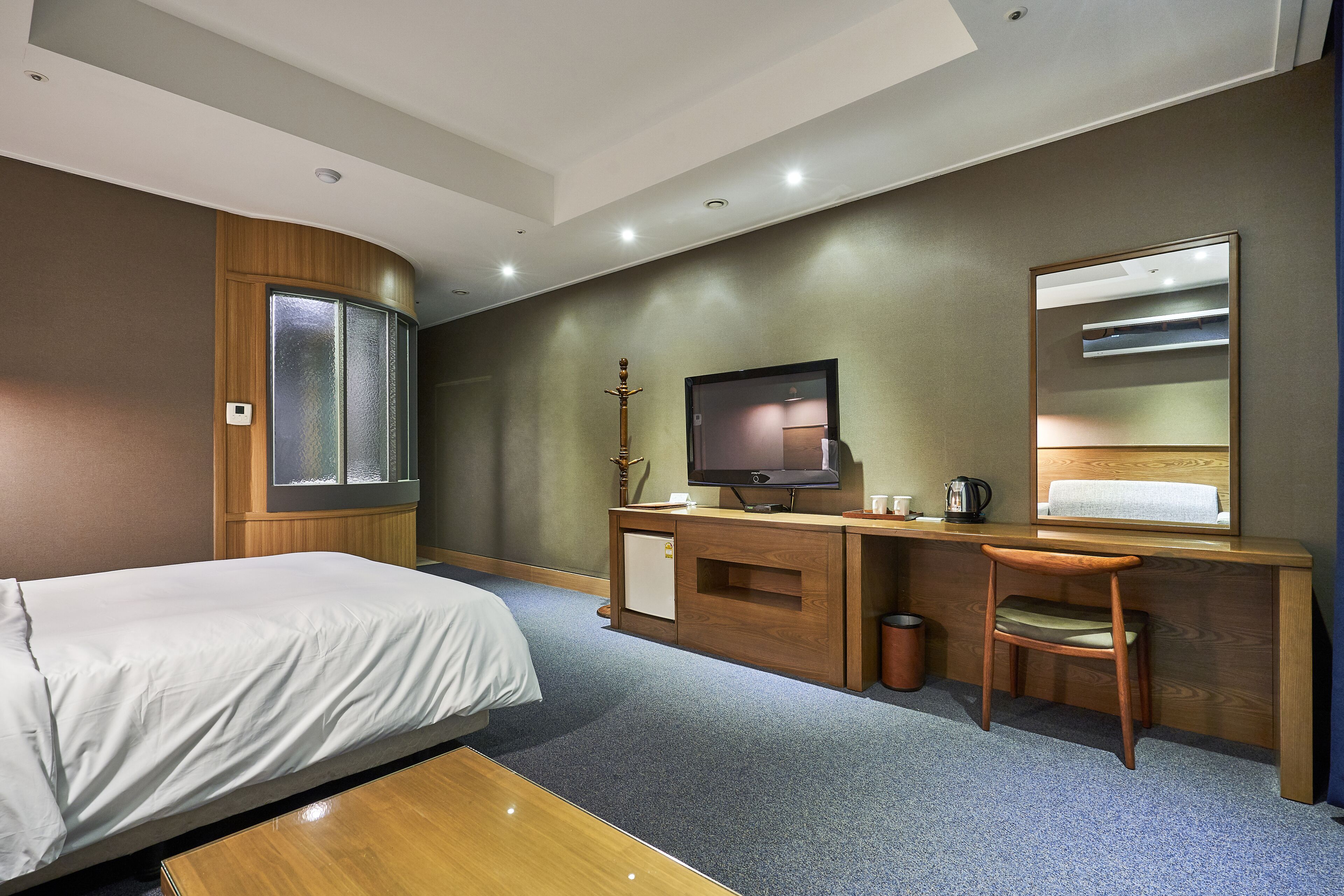 A hotel room with a bed, desk, chair, television, and a small cabinet.
