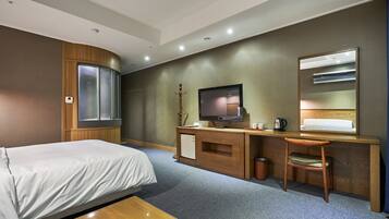 A hotel room with a bed, desk, chair, television, and a small cabinet.