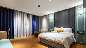 A modern hotel room with a large bed, a bedside table, a chair, and a desk. - Koryo Hotel (Bucheon)