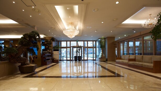 A spacious lobby with a large chandelier, a reception desk, and a seating area. - Koryo Hotel (Bucheon)