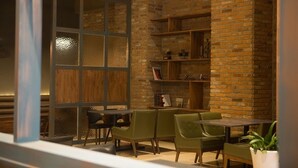 A cozy dining area with brick walls, wooden shelves, and green upholstered chairs. - Koryo Hotel (Bucheon)